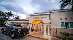 Exterior of Palm Beach Public School with pickup truck parked in front at dawn.