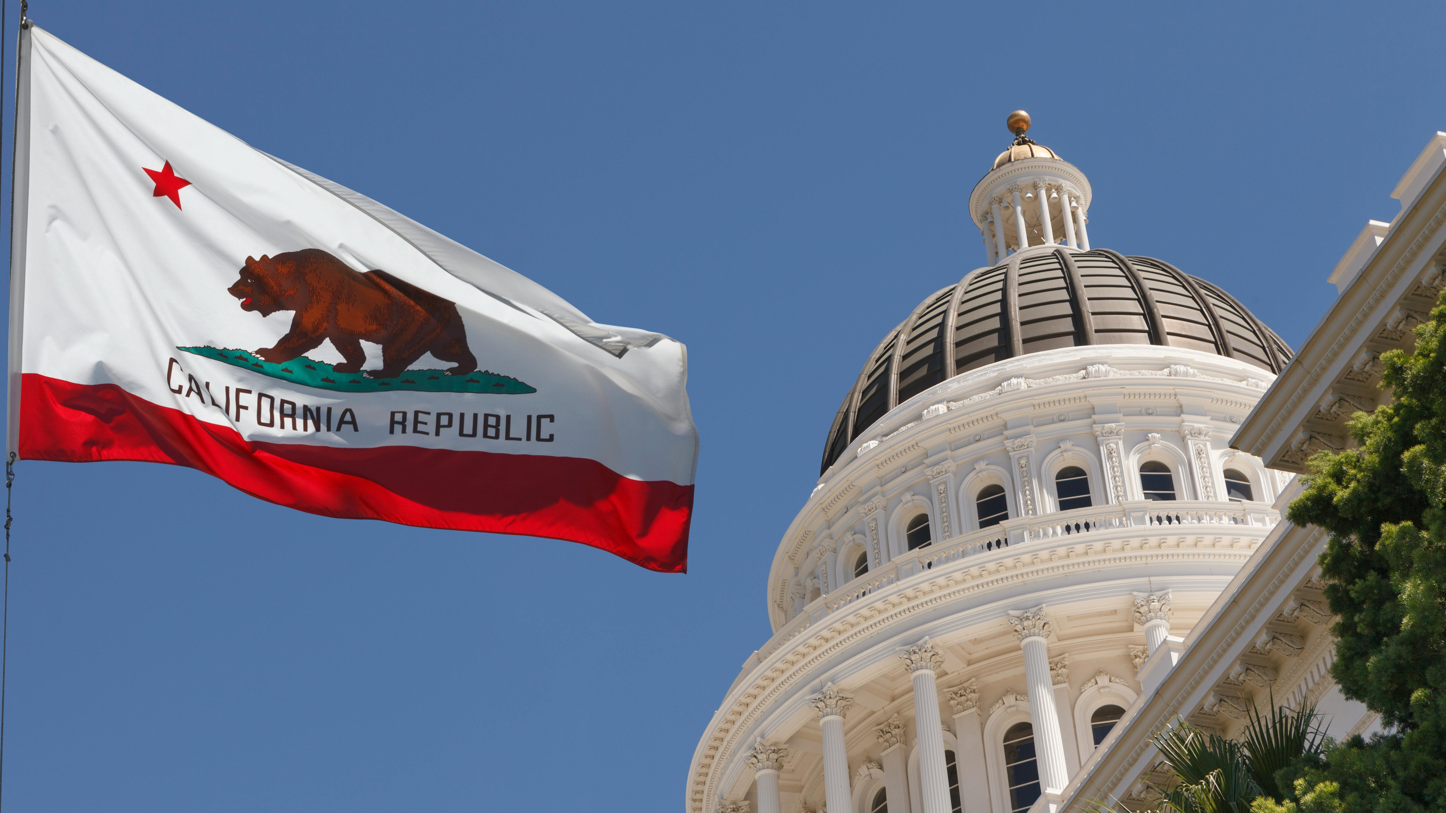 Flag of California flying outside state legislature building.