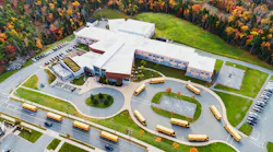 A fleet of school buses leave an elementary school after morning drop offs.