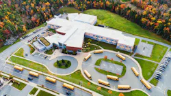 A fleet of school buses leave an elementary school after morning drop offs.