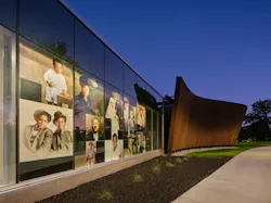 Exterior of new Jim Crow Museum at night featuring lighted glass wall containing historic photography from the collection.