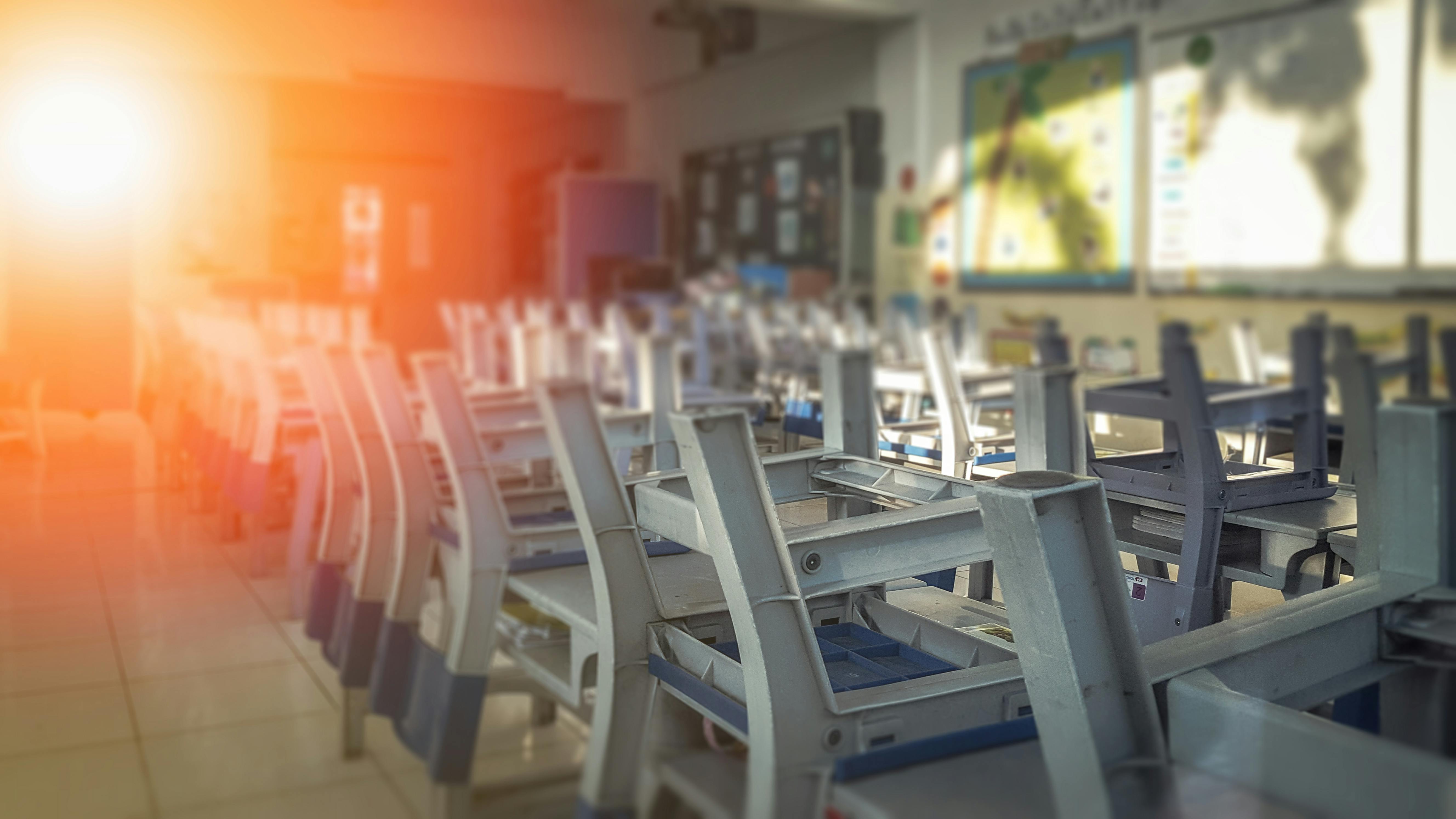 Dark, empty school classroom with chairs stacked upside down on desks.