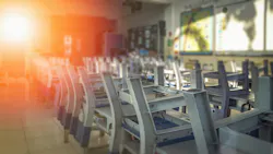 Dark, empty school classroom with chairs stacked upside down on desks.