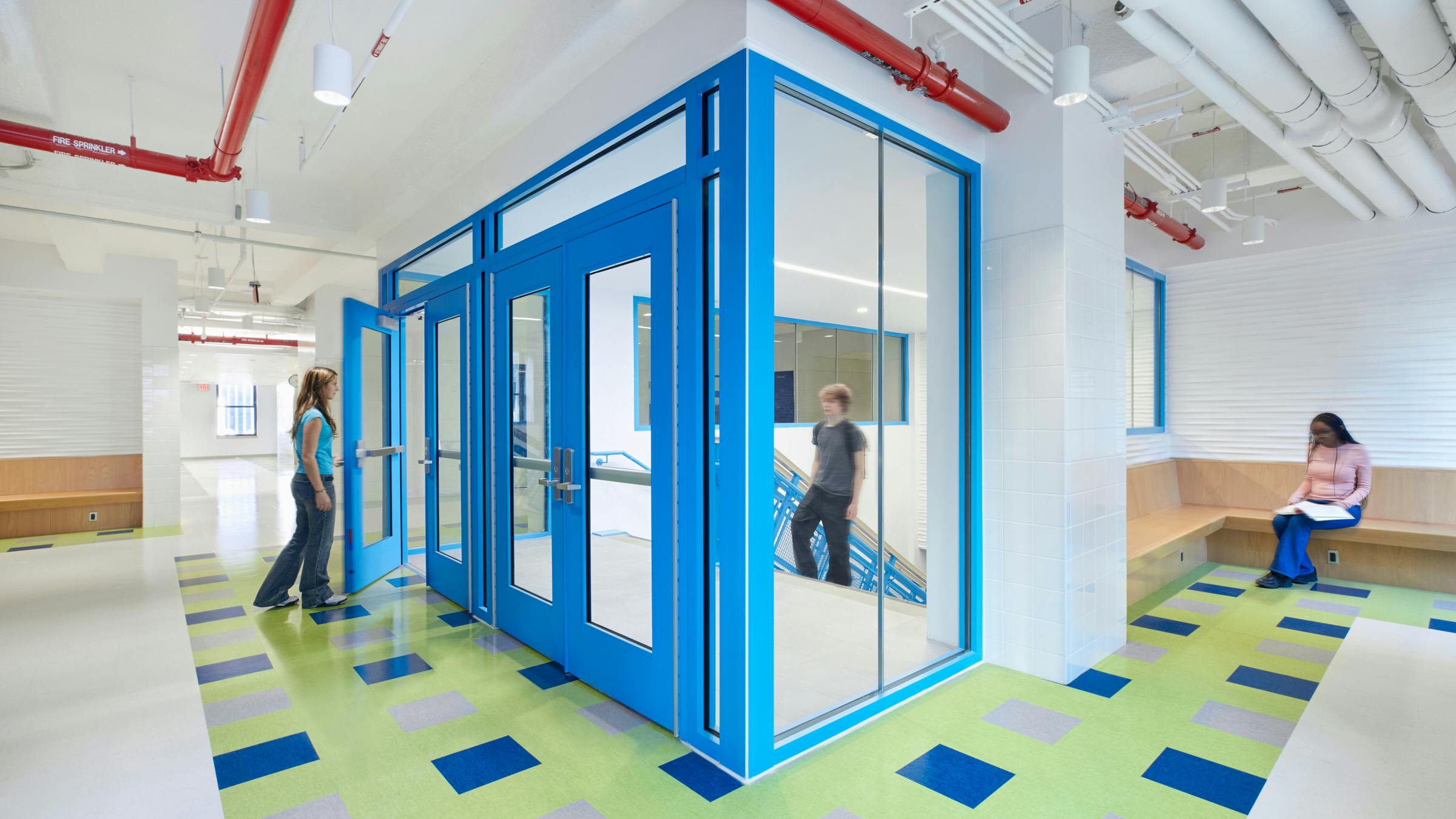 Students walk in bright, colorful hallway next to entrance to stairwell.