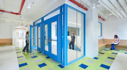 Students walk in bright, colorful hallway next to entrance to stairwell.