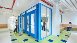 Students walk in bright, colorful hallway next to entrance to stairwell.