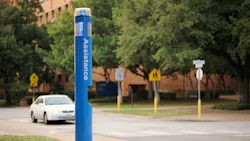 Blue emergency phone on college campus with car in the background.