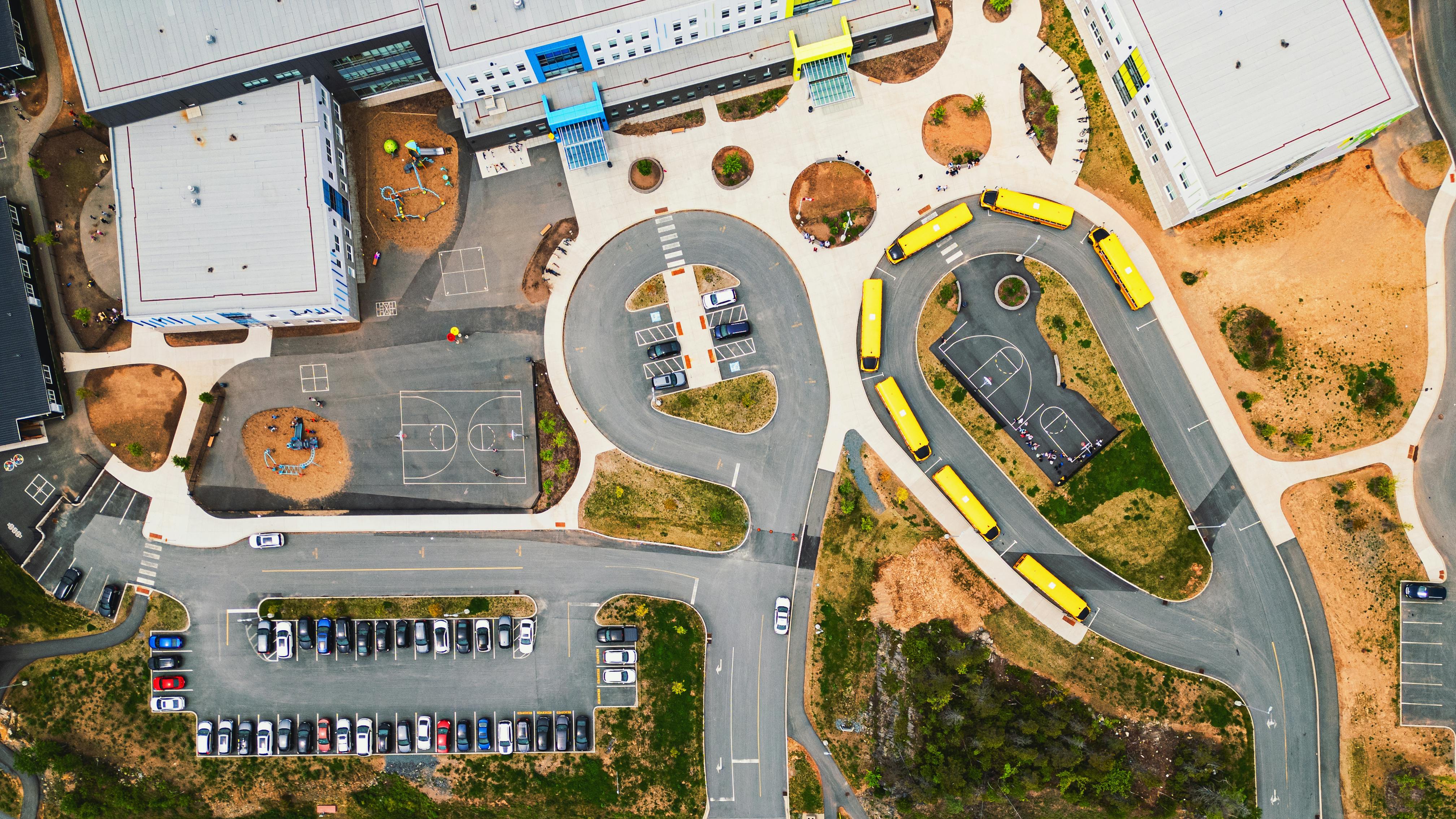 Aerial view of school campus with bus loop and parking lot in view of building.