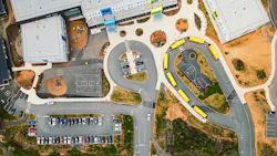 Aerial view of school campus with bus loop and parking lot in view of building.