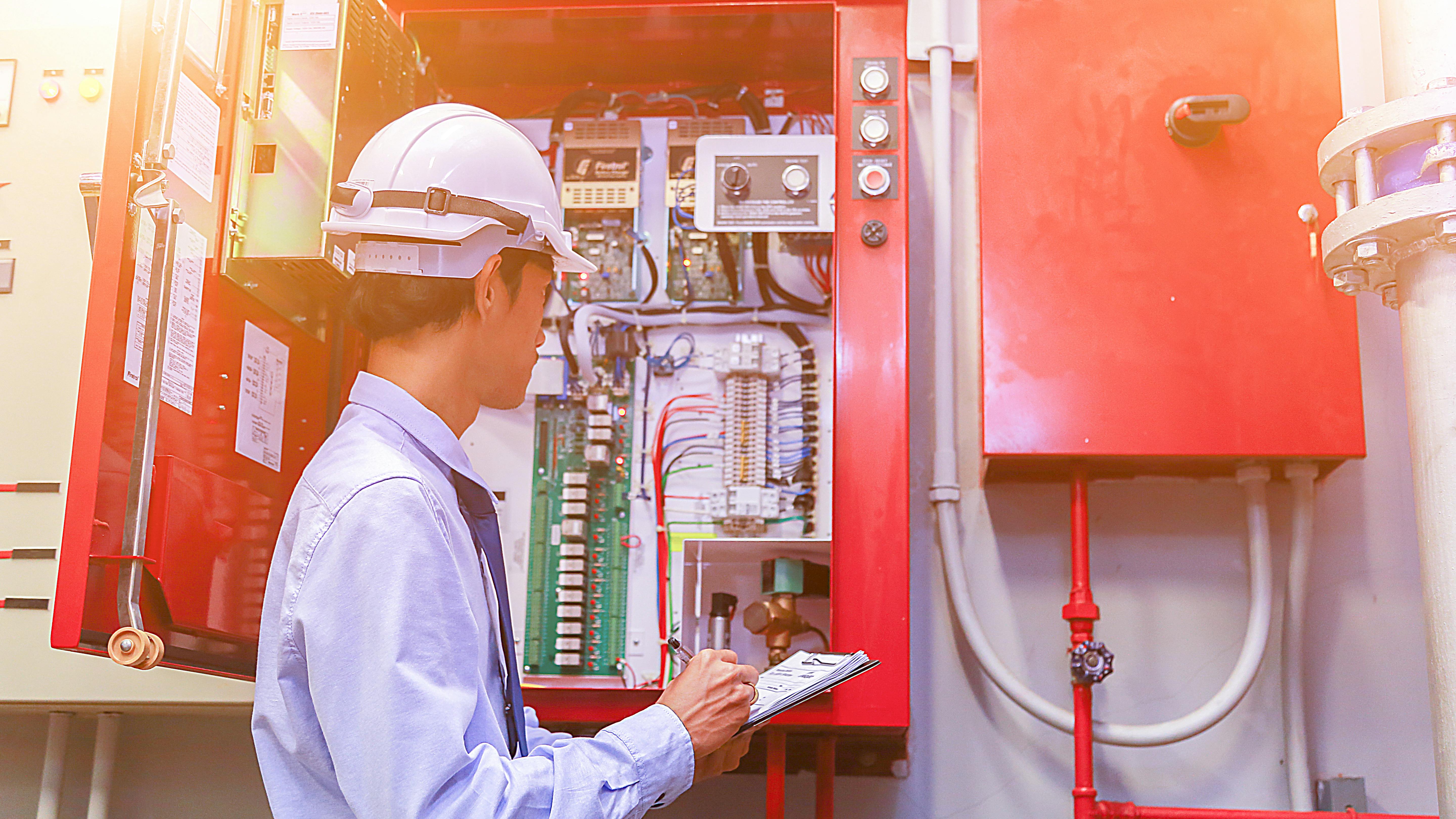 Engineer inspects fire alarm system in commercial building.