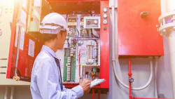 Engineer inspects fire alarm system in commercial building.