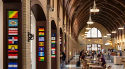 Newly renovated, historic dining hall with students sitting at tables beneath large, vaulted ceiling with curved wood beams.