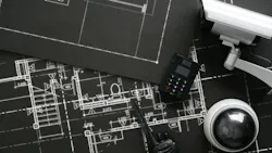 Building blueprints in black & white with security camera and equipment sitting on top.